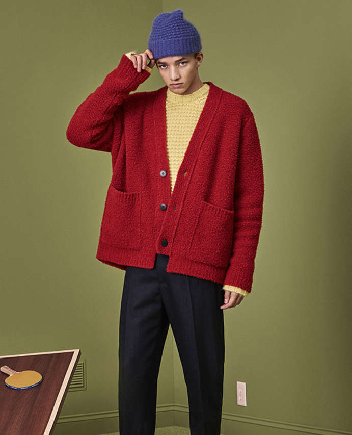 A man wearing a beanie hat, yellow jumper and red cardigan