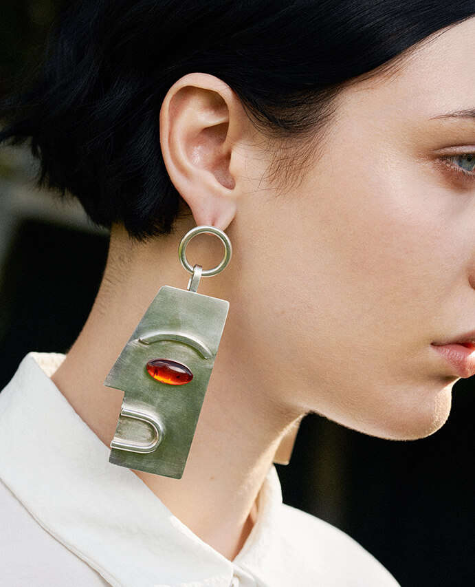 Model wears sculptural earrings