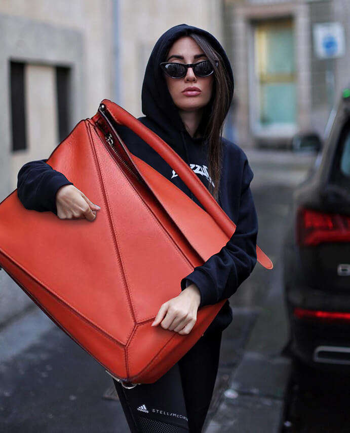 A guest poses with a Loewe Puzzle bag after the Miu Miu show at